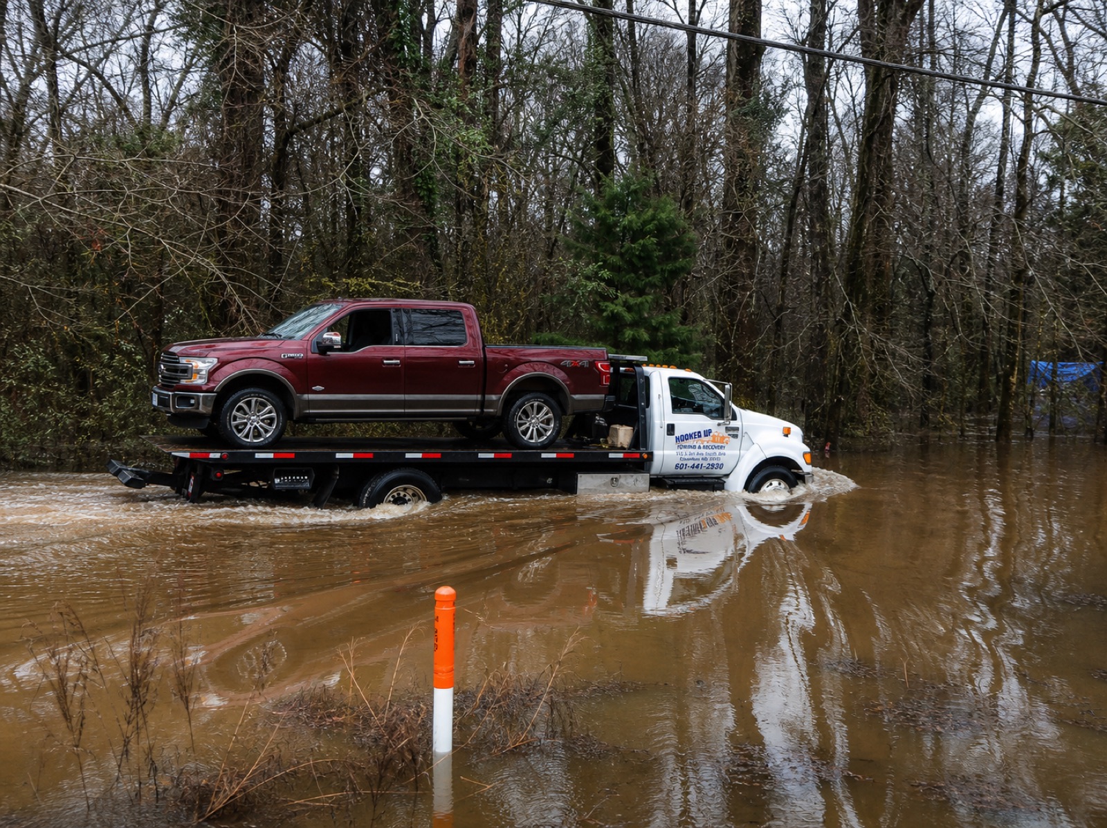 Hooked Up Towing & Recovery flatbed hauling a pickup through flood water